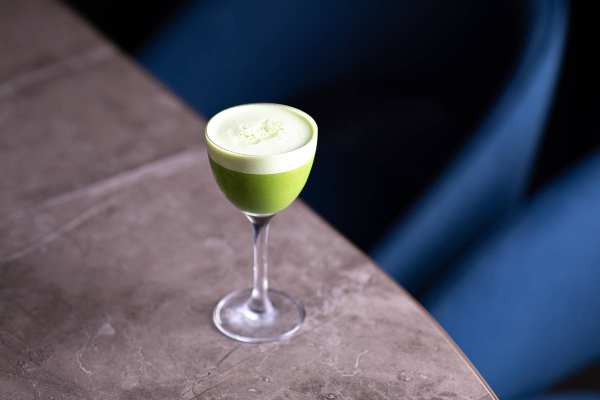 a bright green non-alcoholic cocktail served in a fancy coupe glass, with a head of soft fluffy white foam