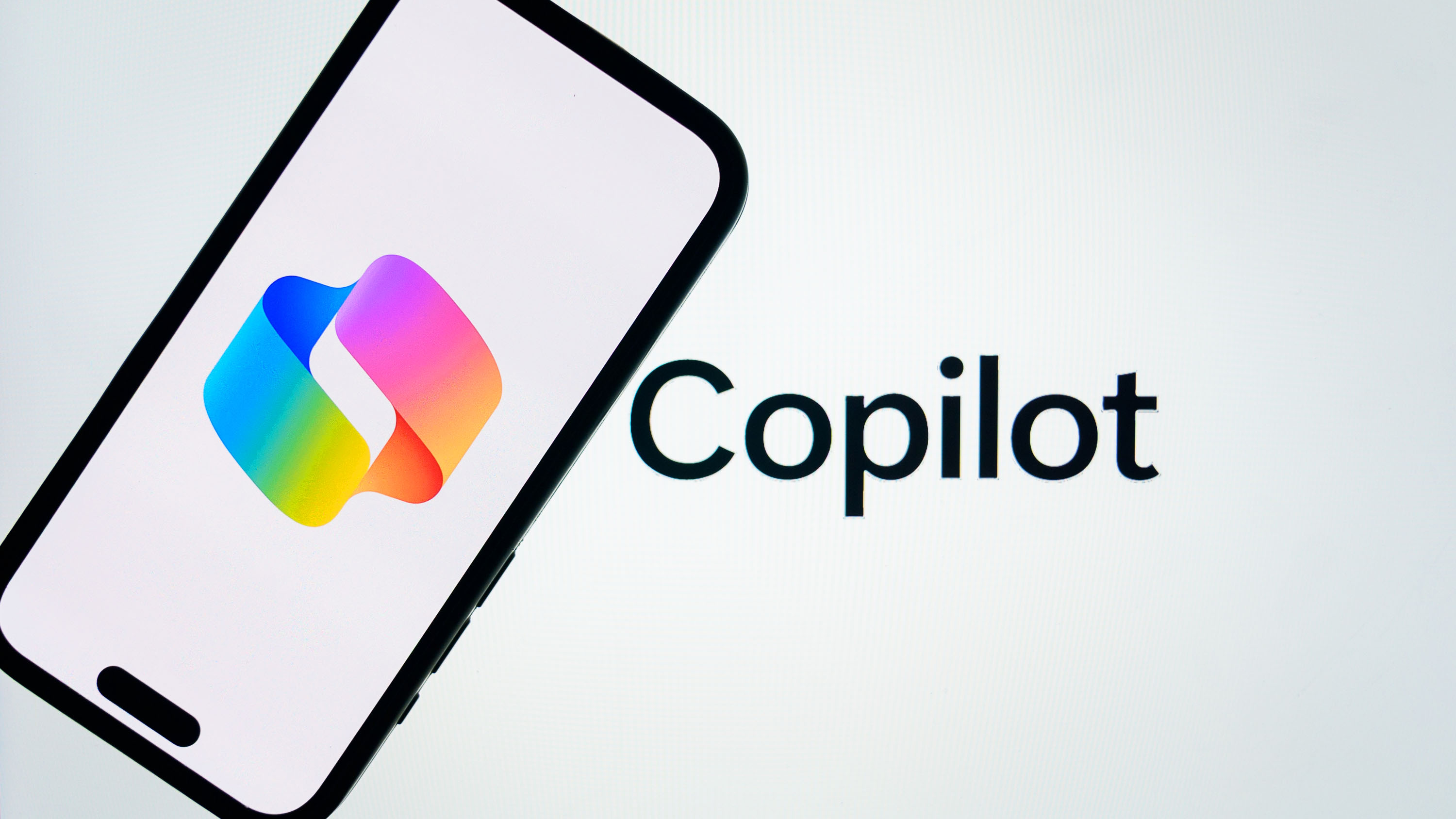 In this photo illustration, 'Microsoft Copilot' logo is displayed on mobile phone screen in front of a screen displaying the inscription of 'Copilot' in Ankara, Turkiye on March 14, 2025.