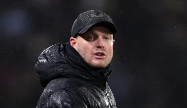Middlesbrough manager Kim Hellberg looks on during a game wearing a baseball cap and big coat