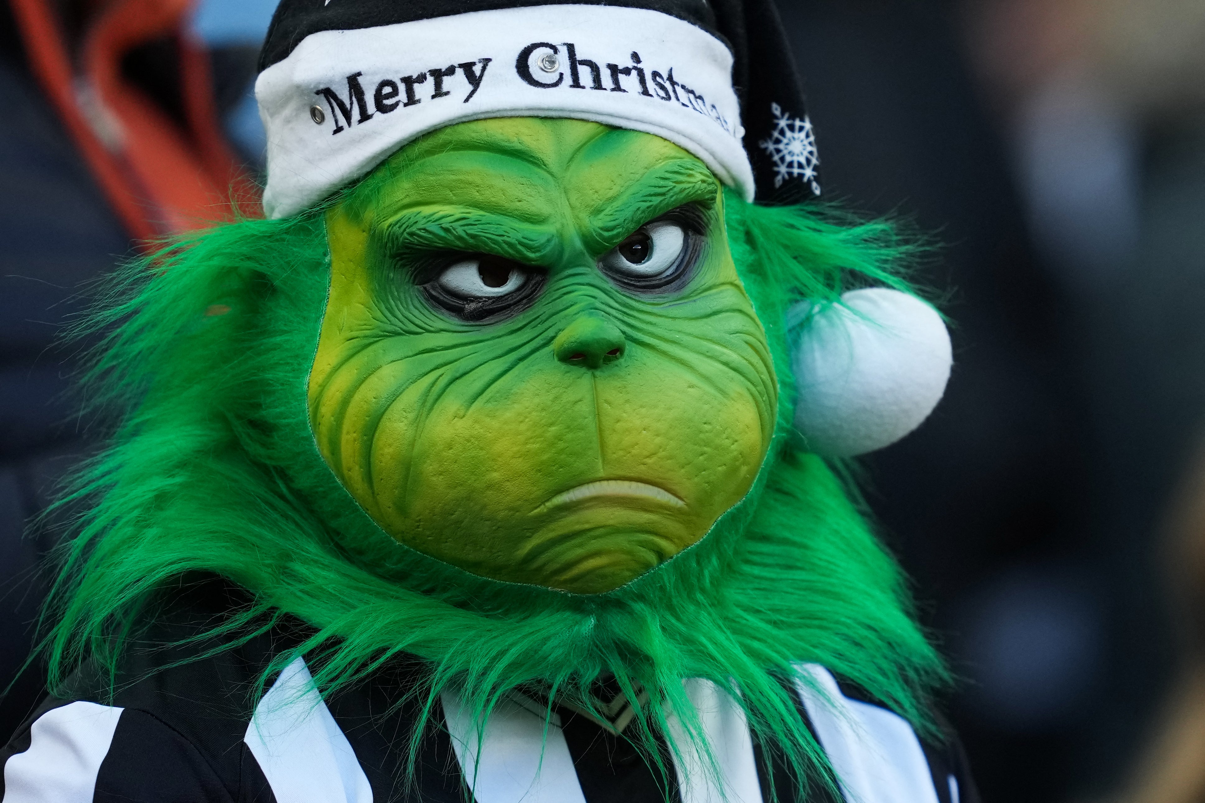 A Newcastle United fan wears a Grinch mask