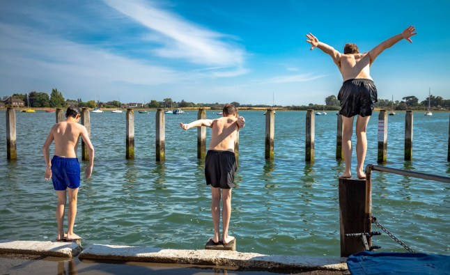 Three teenage boys ready themselves to dive into the sea at high tide at Bosham, West Sussex, UK. (Photo by: Andy Soloman/UCG/Universal Images Group via Getty Images)