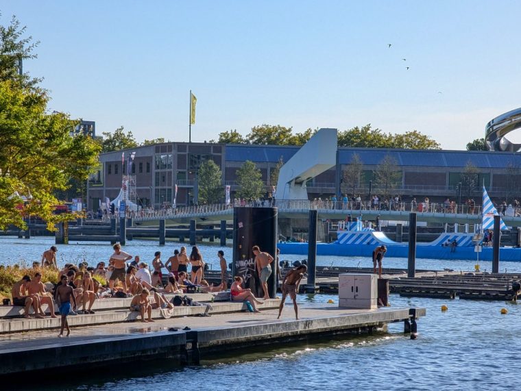 Locals enjoy an early evening at Zwembad Rijnhaven in Rotterdam, Netherlands, on September 7, 2025. It is an open-air swimming location in central Rotterdam between Kop van Zuid and Katendrecht. The swimming area is equipped with a bridge and ladders for entry and exit, and the quay can be used for jumping into the harbor. Steps and platforms around the water provide space for sitting. Visitors use the area for swimming, relaxing, and watching the sunset over the port. (Photo by Michael Nguyen/NurPhoto via Getty Images)