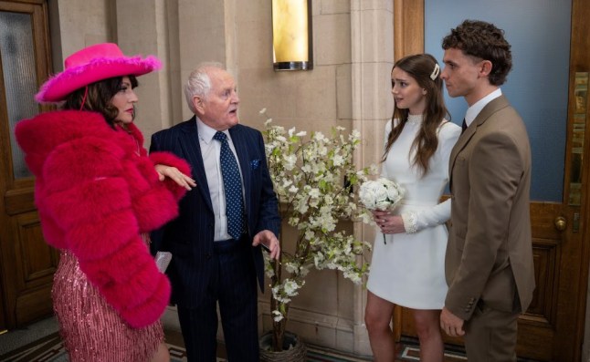 Kerry and Pollard, dressed in wedding attire, confront Sarah and Jacob, also dressed in wedding outfits, in Emmerdale