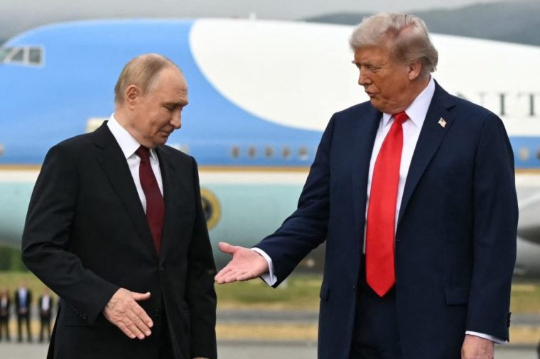 TOPSHOT - AFP PICTURES OF THE YEAR 2025 US President Donald Trump (R) reaches out to shake hands with Russian President Vladimir Putin as they pose on a podium on the tarmac after arrival at Joint Base Elmendorf-Richardson in Anchorage, Alaska, on August 15, 2025.. Putin is in Alaska at the invitation of Trump in his first visit to a Western country since he ordered the 2022 invasion of Ukraine that has killed tens of thousands of people. (Photo by ANDREW CABALLERO-REYNOLDS / AFP via Getty Images) / AFP PICTURES OF THE YEAR 2025