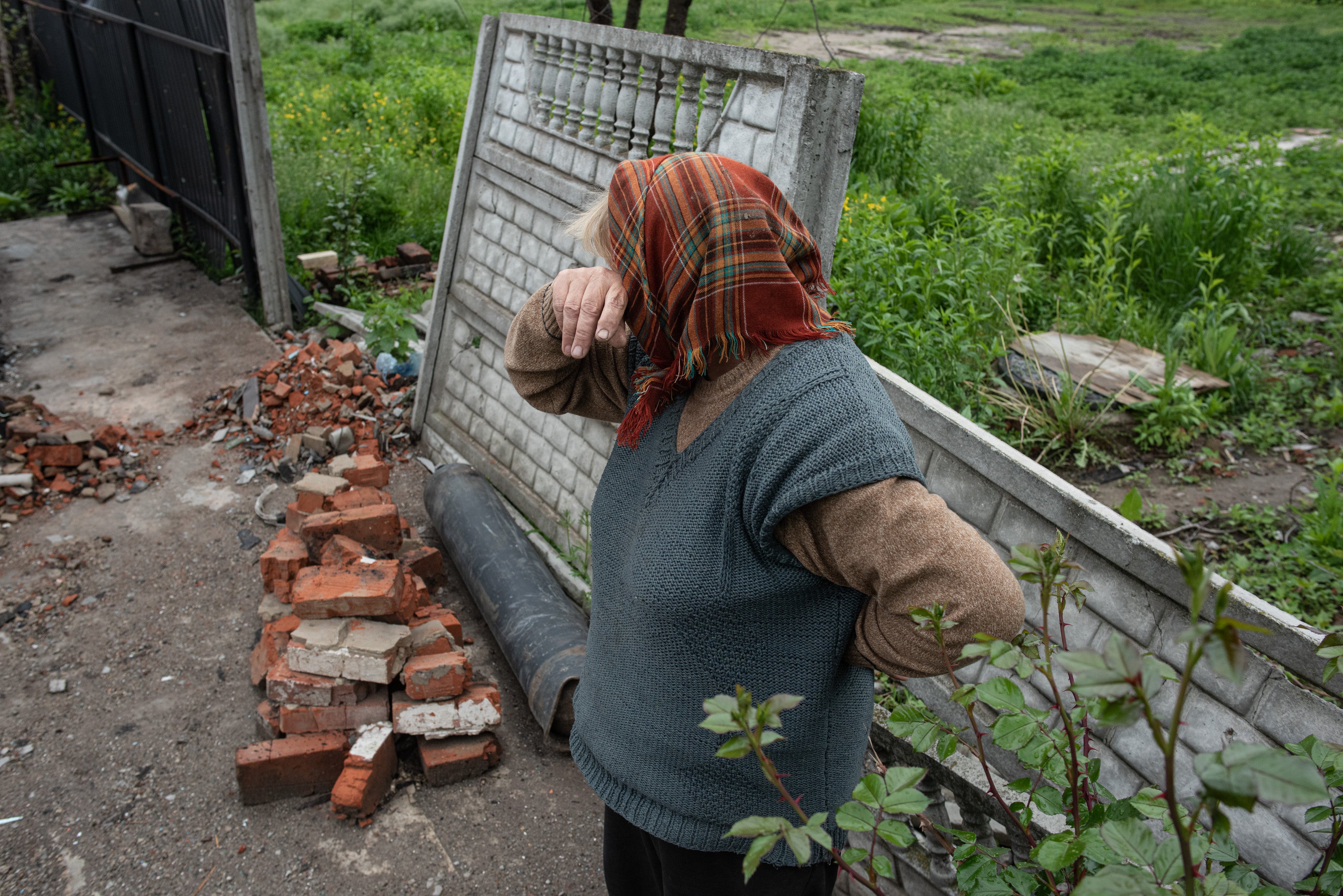 An elderly woman cries in front of her burned house in May 2022 in Novoselivka, Ukraine
