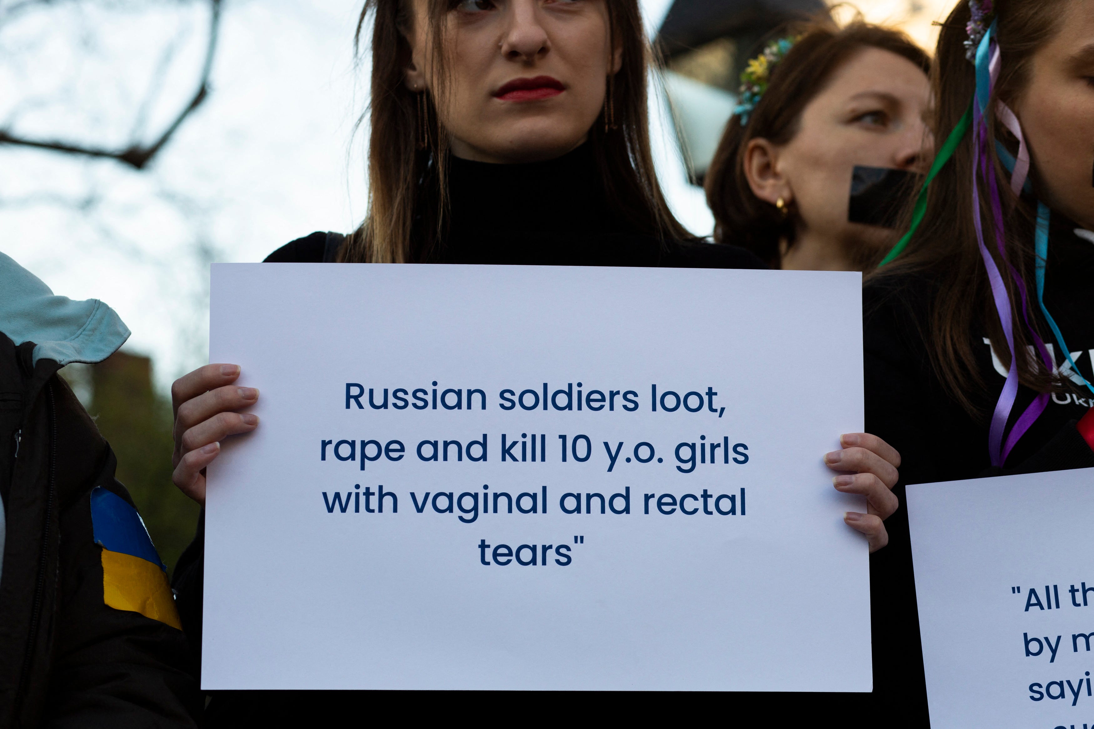 A woman holds a sign denouncing sexual atrocities during a flashmob protest against sexual abuse by Russian soldiers in Ukraine, at Washington Square Park in New York City, in April 2022