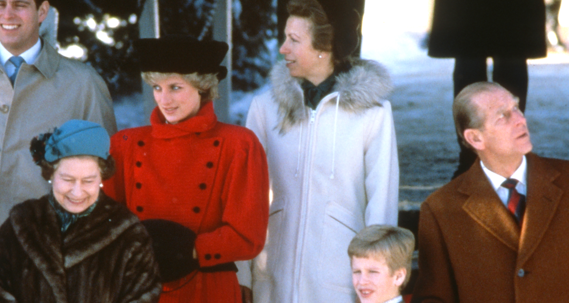 Queen Elizabeth in a fur coat, Princess Diana in a red coat, Princess Anne in a white coat and Prince Philip looking up to the side outside church at Christmas