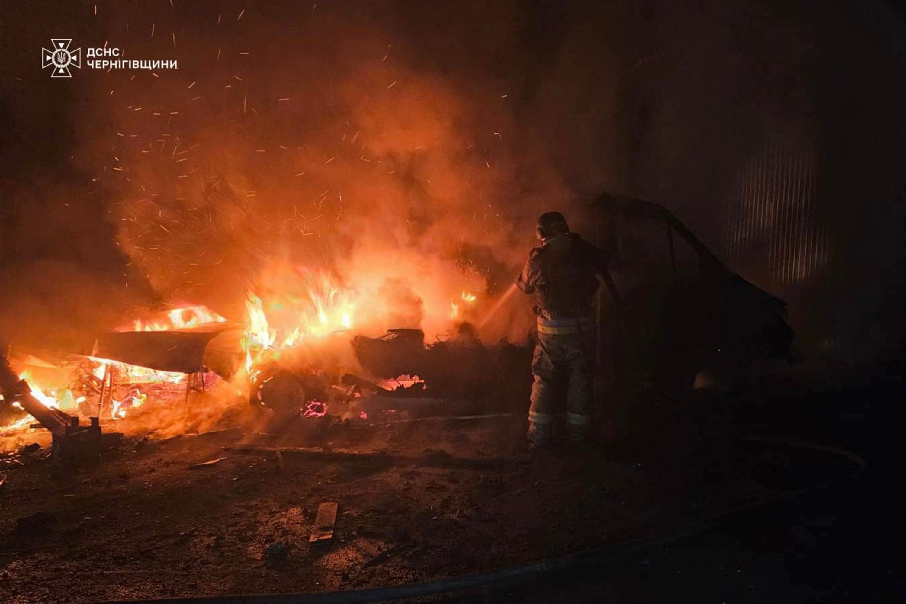 Ukrainians work to extinguish a fire following a drone strike in the Chernihiv region
