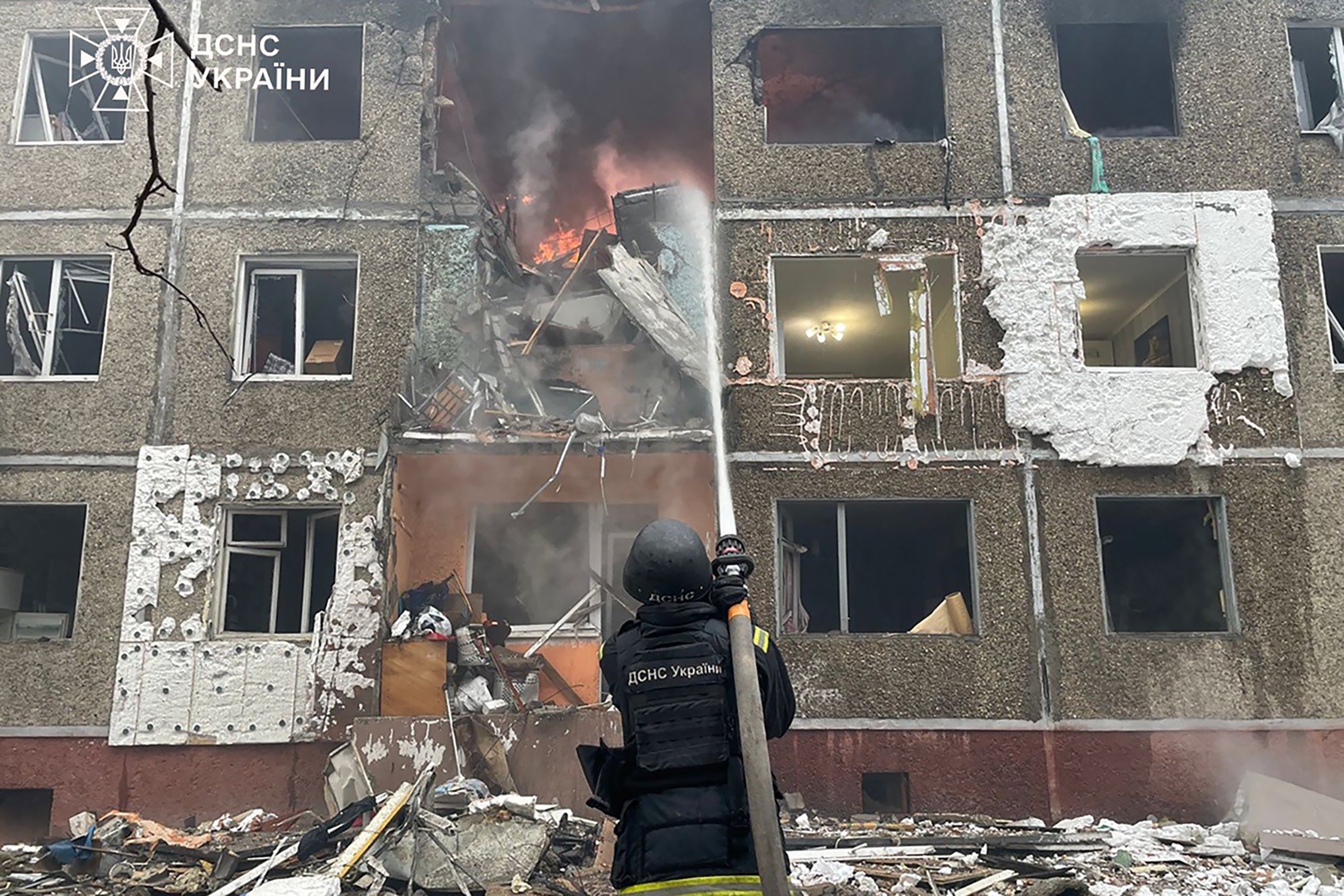 A Ukrainian rescuer extinguishes a fire at a damaged residential building following a drone strike in Chernihiv, amid the Russian invasion of Ukraine