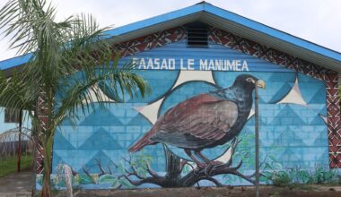 Photo of a the exterior of a building on which is a mural of a large bird as viewed from the side. Above the bird it says, "PAASAO LE MANUMEA."