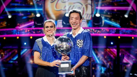 BBC  Karen Carney and Carlos Gu with their trophy after winning the 2025 series of Strictly Come Dancing