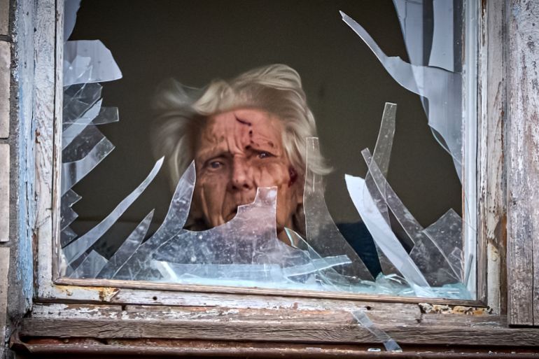 An injured elderly woman looks out of her broken window as an apartment building was hit by a Russian drone during an aerial attack in Kyiv, Ukraine, Tuesday, Dec. 23, 2025. (AP Photo/Efrem Lukatsky)
