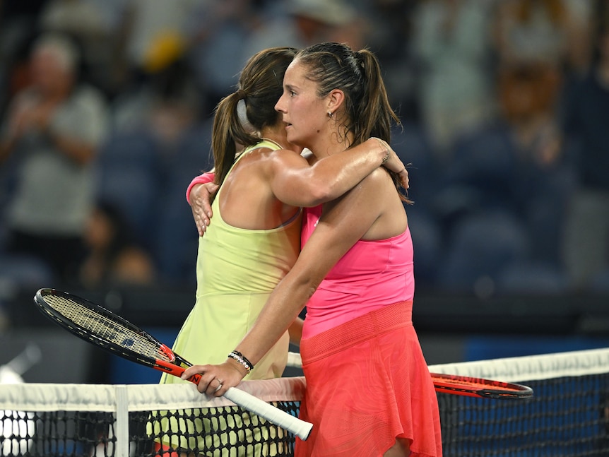 Two female tennis players hug at the net after a match at the Australian Open.