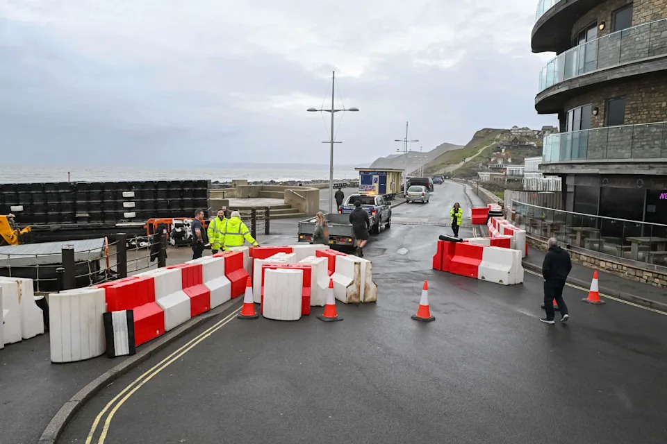 West Bay, Dorset, UK.  8th December 2025.  UK Weather.  Temporary flood barriers being deployed by Dorset Council on the seafront at West Bay in Dorset ahead of Storm Bram which is due to hit tonight and tomorrow.  Picture Credit: Graham Hunt/Alamy Live News