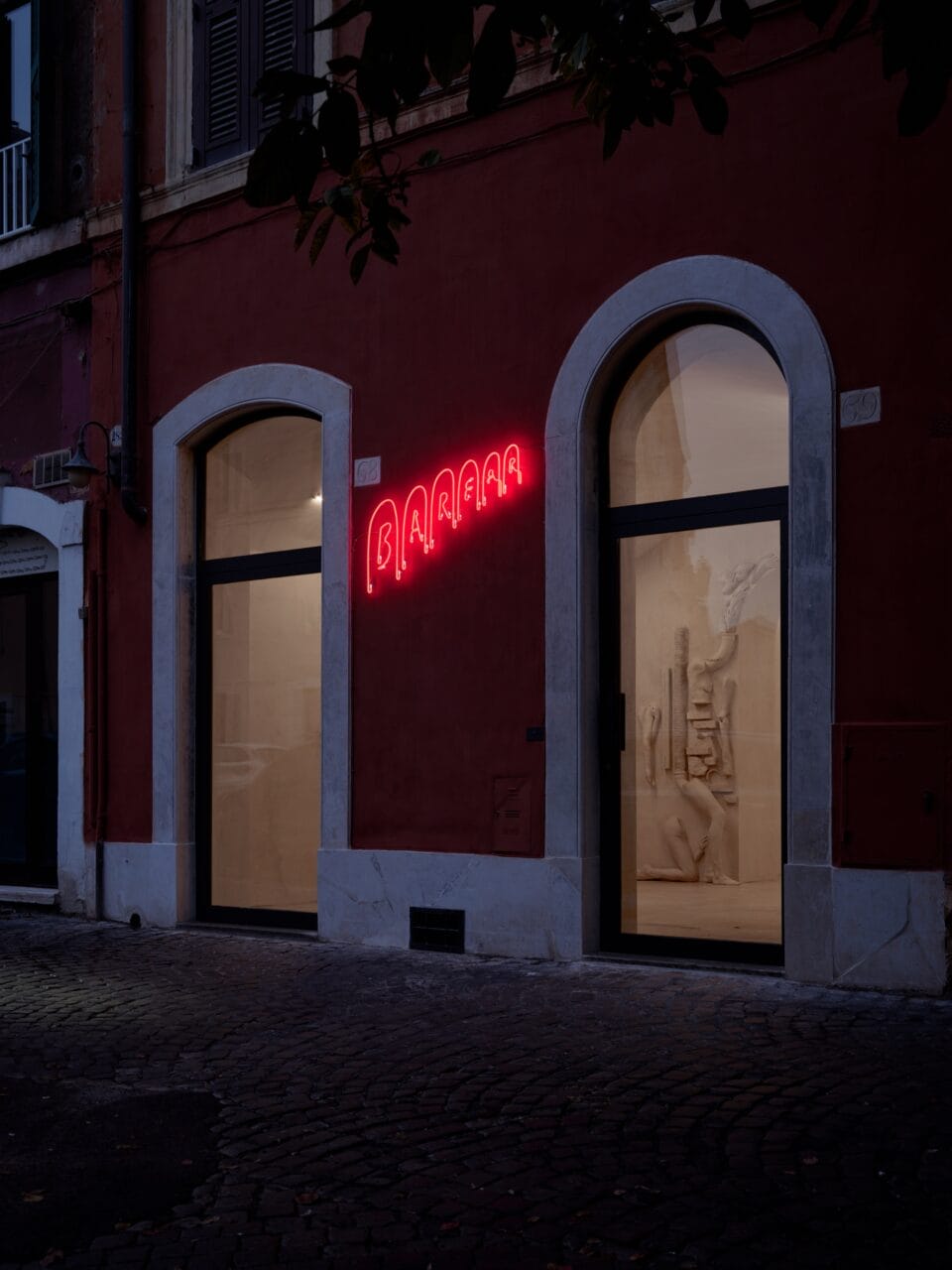 The exterior of an art gallery's brick facade with a neon sign that reads "BAR FAR"