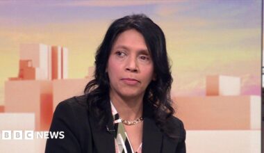 Dr Halima Begum sitting down wearing a black jacket and colourful top. She has dark, shoulder-length hair.