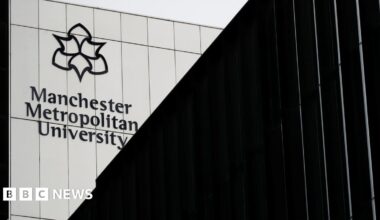 Exterior shot of a metal-covered building with the Manchester Metropolitan University name and logo on it.