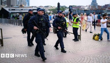 Five armed police holding guns and wearing black uniforms.
