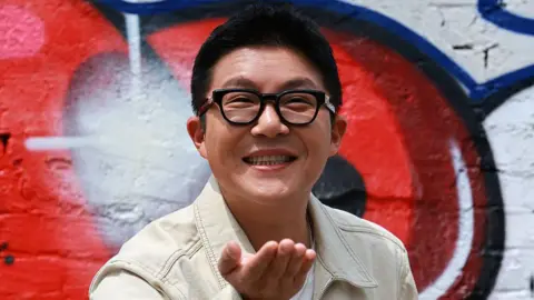 Getty Images Cho Sae-ho smiling as he wears a white denim jacket and black-rimmed glasses