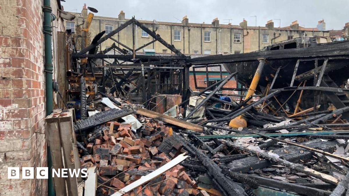 One of Underfall Yard's buildings is shown completely gutted by the fire. Just the frame of the building remains, with the roof and even exterior walls completely caved in. Piles of rubble fill the foreground.