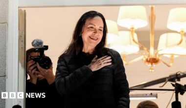 Maria Corina Machado jumps over barricades outside the Grand Hotel in Oslo to greet cheering supporters as security looks on.