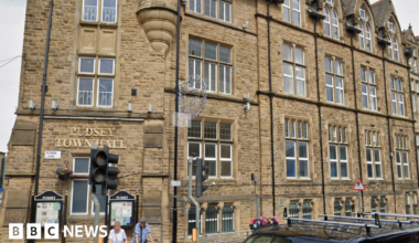 A large Victorian building with the words Pudsey Town Hall written above one of several windows in gold lettering