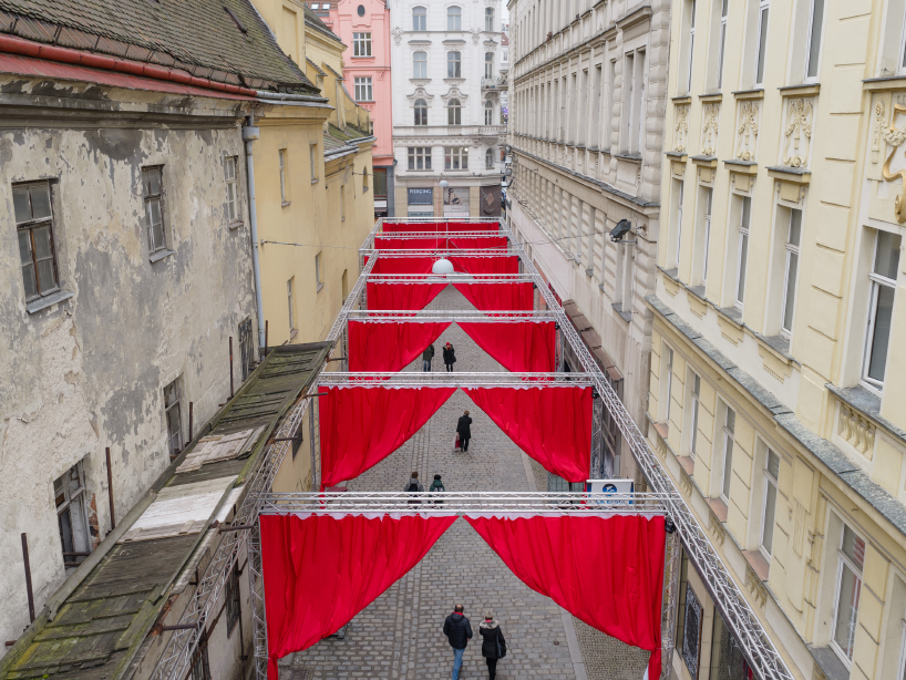red and white curtains transform czech historic center’s pathways into christmas installation