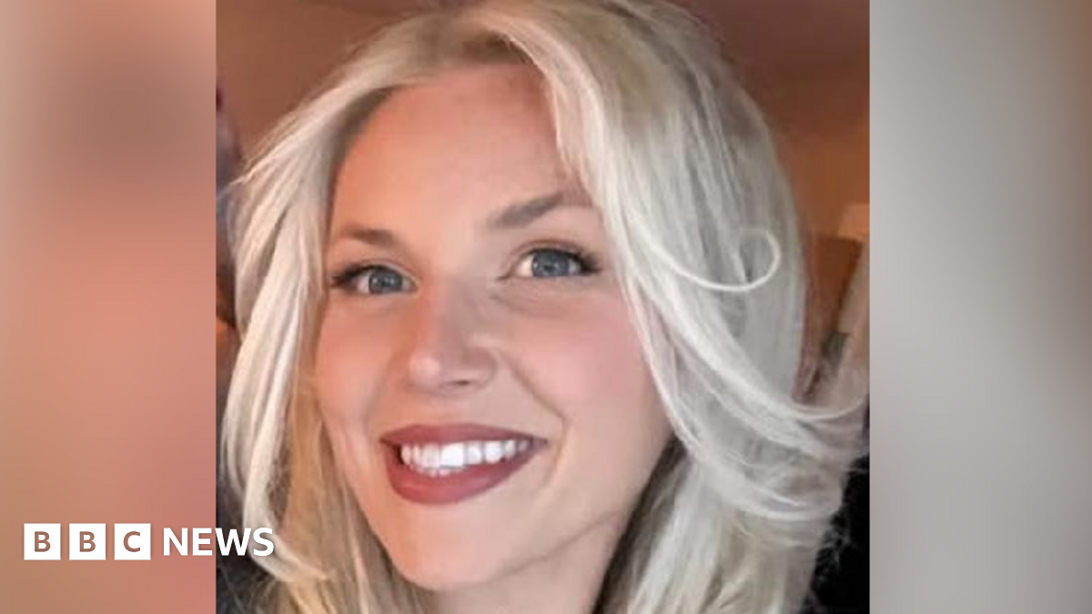 A woman smiles at the camera. It is a selfie and she has long blonde hair and blue eyes.