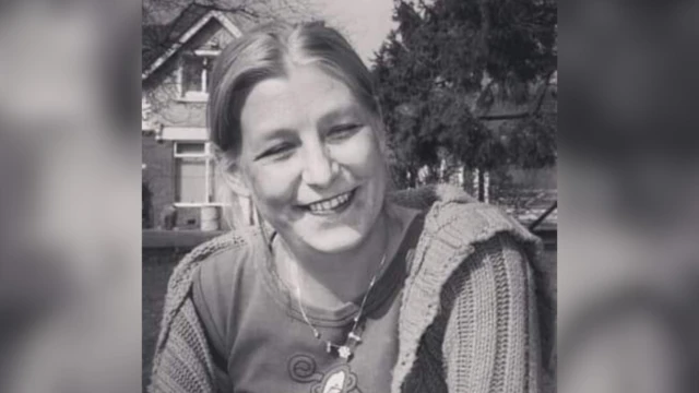Black and white image of Dawn Sturgess smiling with her hair tied back and a loose cardigan over a T-shirt.