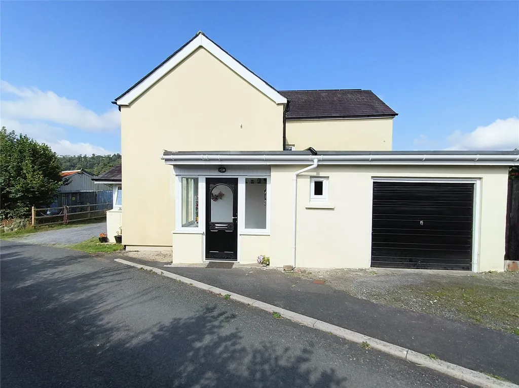 Modern cream-coloured house with black front door and garage, located in rural Carmarthenshire.