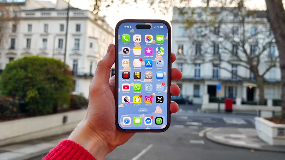 An iPhone 17 Pro being held in the hand outside.