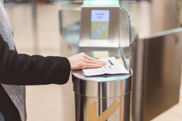 A traveler scans a boarding pass at an airport gate kiosk with their hand resting on the document.