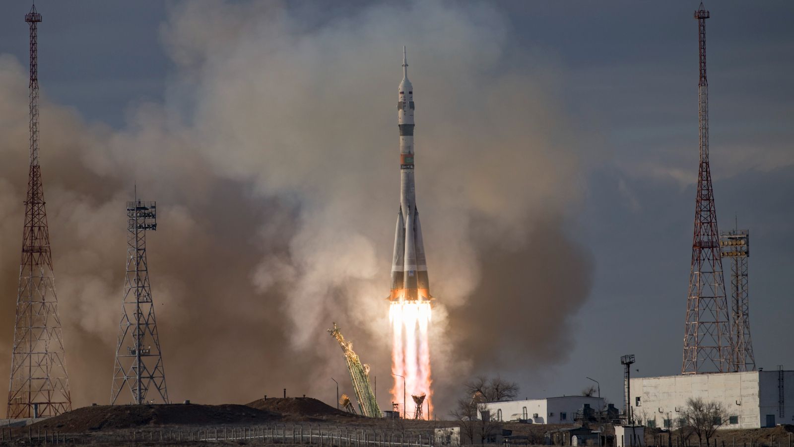 A Soyuz rocket taking off from a launchpad in daylight hours