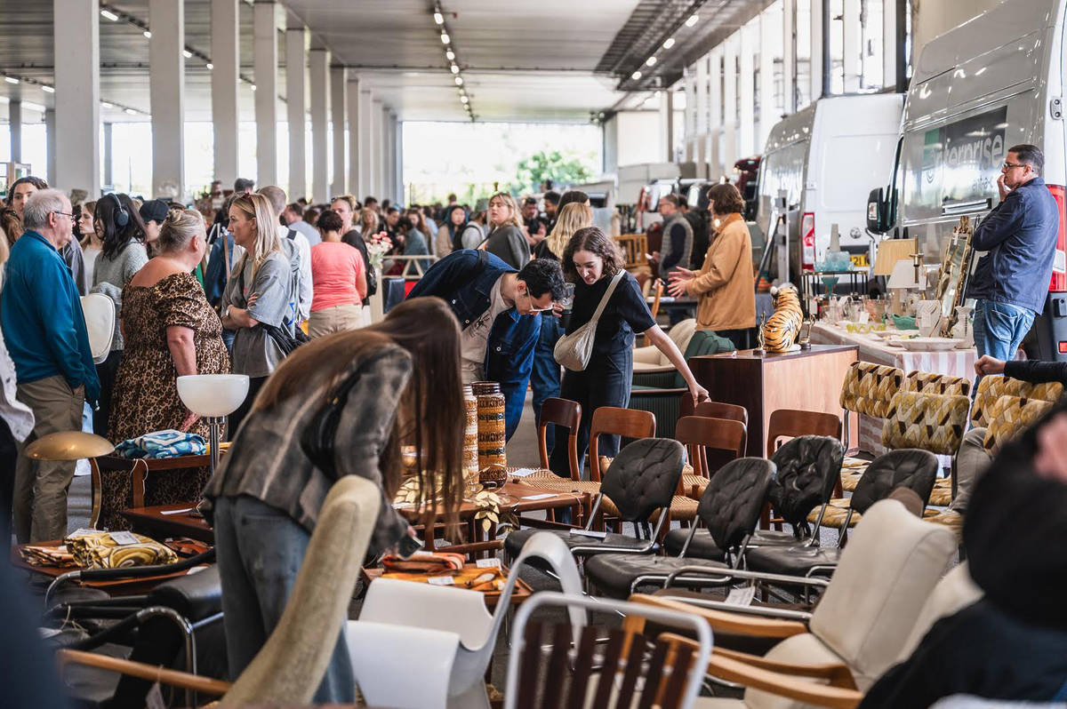 a huge covered outdoor flea market with countless people browsing furniture and oddities