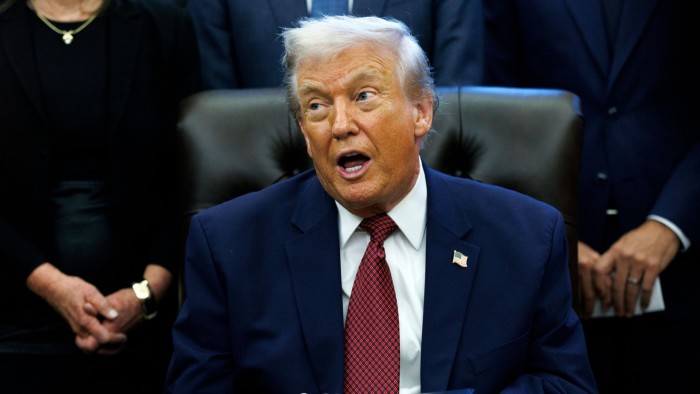 Donald Trump speaks while seated at a desk, surrounded by people, during the announcement of changes to fuel economy standards.