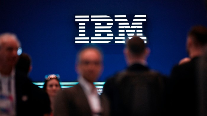 The IBM logo is illuminated above a crowd of people.