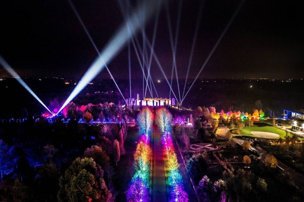 The National Memorial Arboretum from an aerial view full of rainbow-lit trees and spotlights in the air for Illuminated Arboretum
