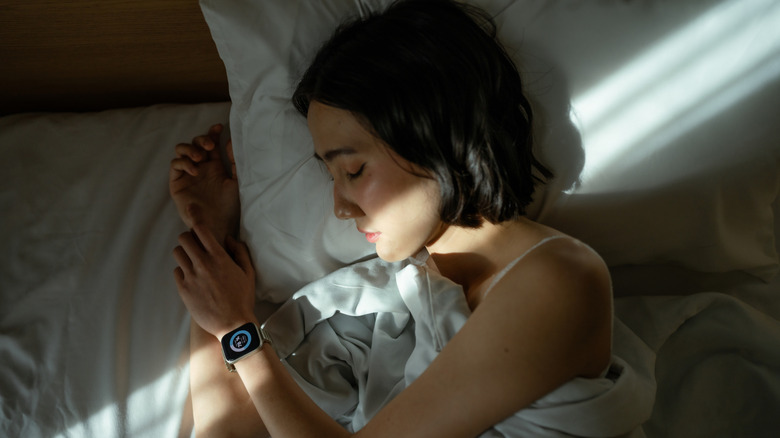 A woman in bed wearing a smart watch.