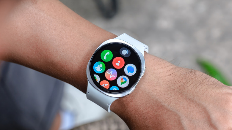 Person looking at a smartwatch on wrist, displaying app icons