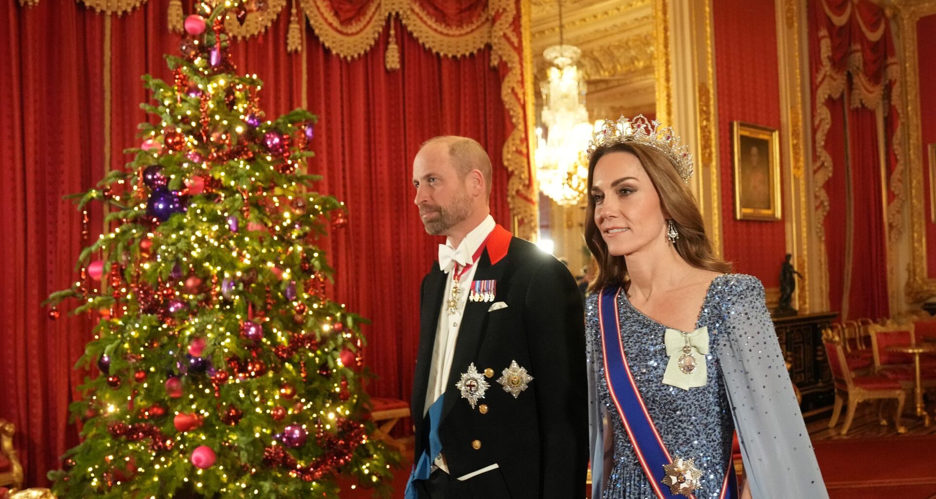 Prince William and Kate Middleton walk past a lit Christmas tree as they arrive at the state banquet for the German President Frank-Walter Steinmeier and his wife Elke Budenbender at Windsor Castle on December 3, 2025