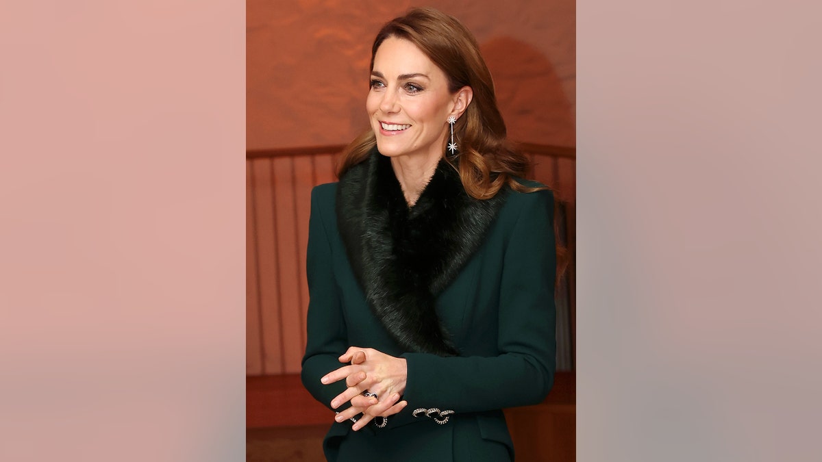 Kate Middleton smiling wearing a hunter green coat.