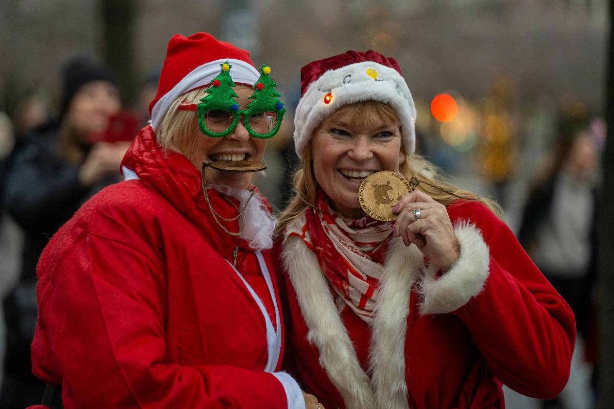 Two women dressed up as Santa Claus holding a medal at a Christmas run