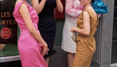 A group of four women in colorful 1960s dresses stand on a sidewalk, engaged in conversation outside a storefront