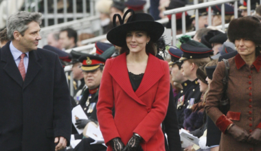 Kate Middleton wearing a red coat and black hat next to her parents