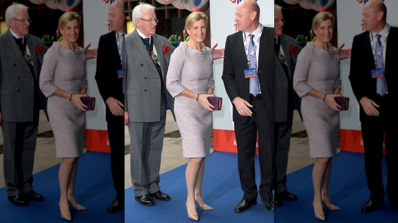 Sophie, Duchess of Edinburgh, surrounded by men in suits while wearing a fitted, patterned dress