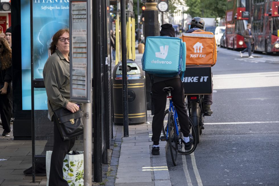 \u200bDeliveroo and Just Eat riders at a London bus stop