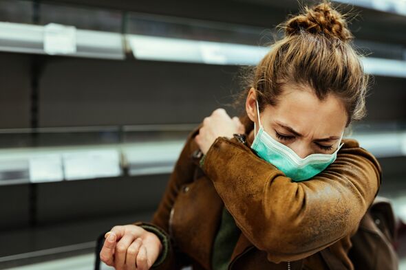 Woman with face mask sneezing into elbow while shopping in grocery store. Woman with face mask sneezing into elbow while shopping in grocery store.