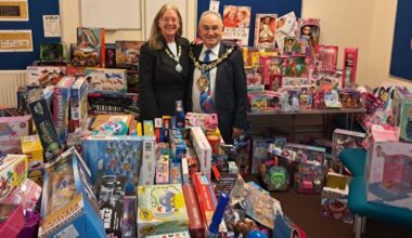 Photo of the Mayoress and Mayor surrounded by hundreds of gifts that were donated