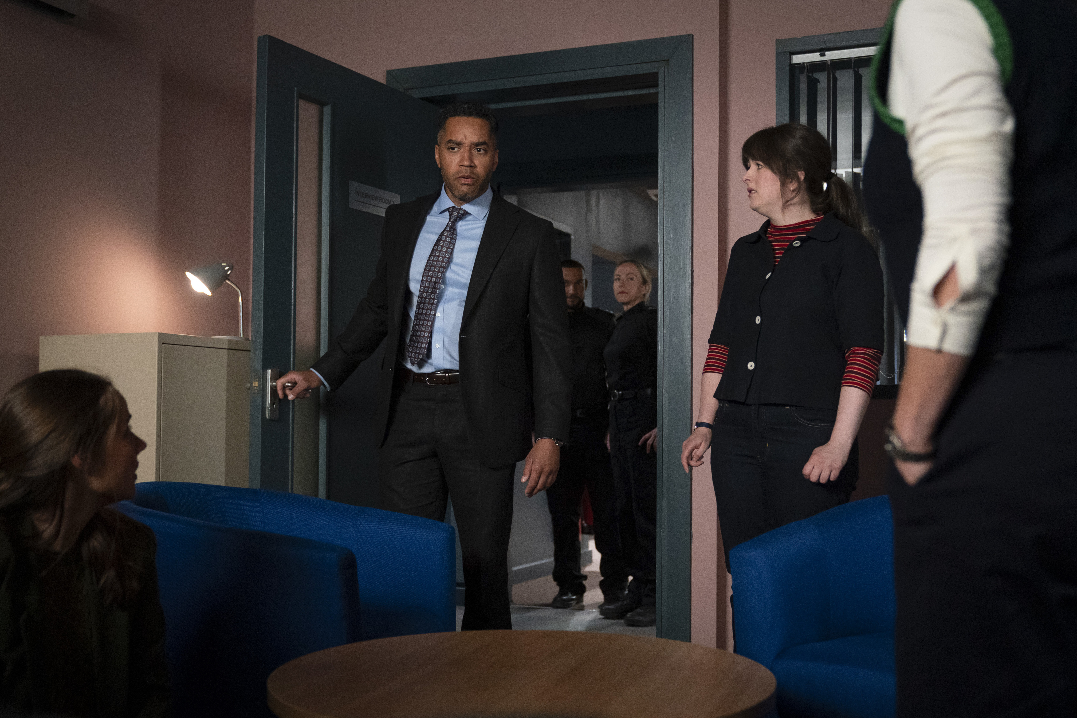 Matt Blake (Samuel Anderson) and DI 'Tosh' McIntosh (Alison O'Donnell) stand in a doorway, with other police officers behind them.