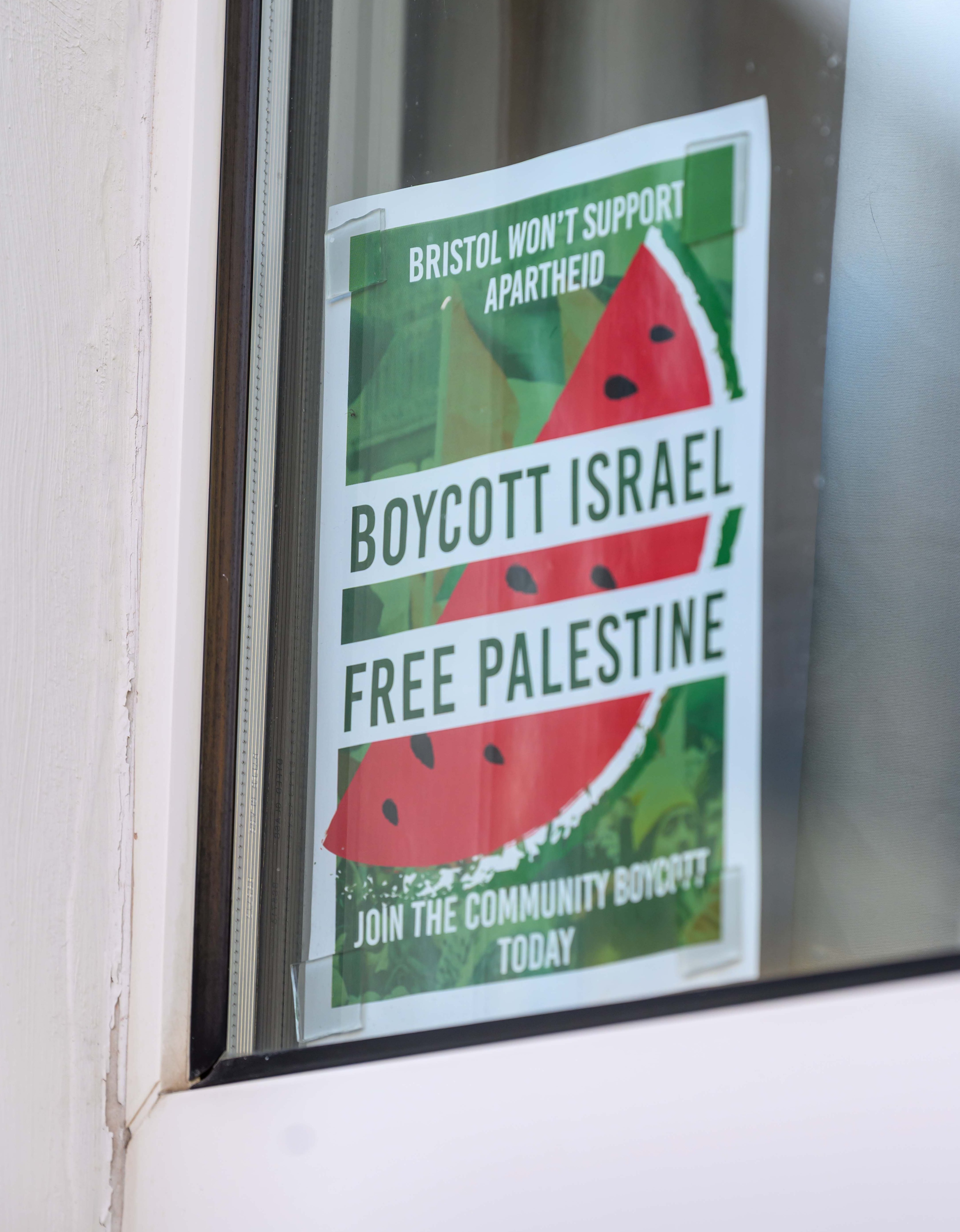 A pro-Palestinian sign in a window displaying text, "Bristol won't support Apartheid", "Boycott Israel", "Free Palestine", and "Join the Community Boycott Today", with a watermelon graphic.